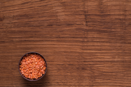 photo of red lentils in metal bowl on brown tableの写真素材
