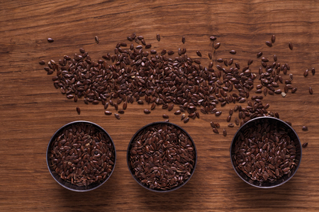 Photo of linseed in metal bowl on brown wooden tableの写真素材