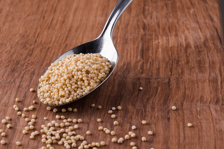 millet photo of on metal spoon on brown wooden tableの写真素材