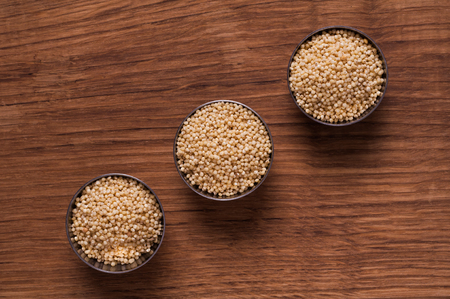 photo of millet in metal bowl on wooden tableの写真素材