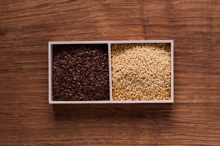 photo of linseed and millet in wooden box on brown wooden table - top viewの写真素材