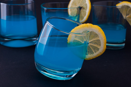 Photo of blue cockail with lemon against black backgroundの写真素材