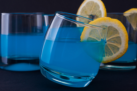 Photo of blue cockail with lemon against black backgroundの写真素材