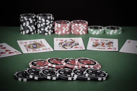 photo of green casino table with royal flush, red and black chips - vintage