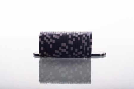 photo of Black casino chips on glass table isolated on whiteの写真素材