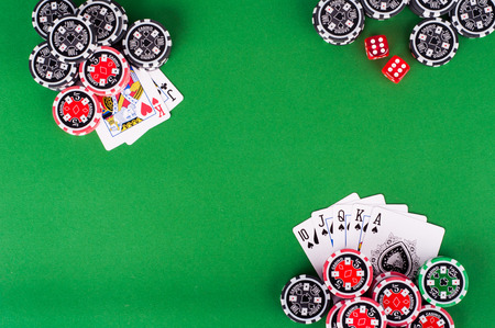 photo of top view of green casino table with royal flush, red and black chips