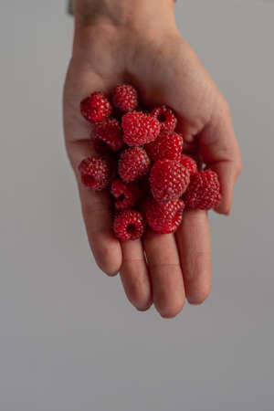 Photo of Young woman holding fresh organic rapsberries in her hand.