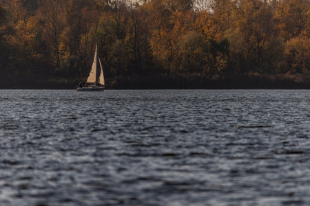 Photo of Sailing boat on the lake against autumn trees backgroundの写真素材
