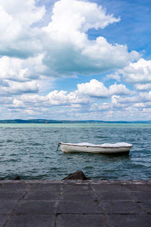 Photo of Boat on the Balaton Lake in Siofok, Hungary. Dramatic Cloudy sky and blue, tourquise water.の写真素材