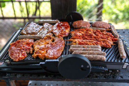 Photo of Delicious beef and pork meat, sausages on BBQ grill. top view.