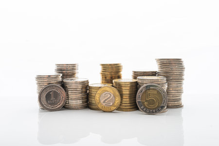 Photo of Coins stacked on white backgroud with smooth reflection. Concept of home buget, saving money, wealth. 1, 2 and 5 PLN coins standing in front of stack.の写真素材