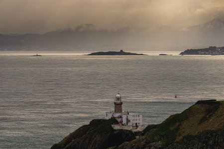 Photo of Howth Cliffs, Dublin, Ireland. Cloudy landscape with Ireland coastline, Howth Lighthouse and North Sea. Howth Cliffs Walk.の写真素材