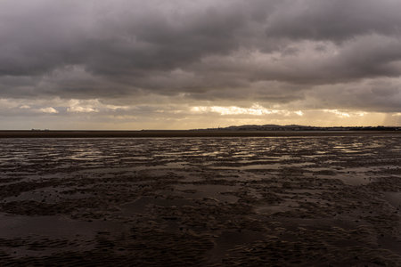 Dramatic, moody atmosphere over Sandymount Beach, Dublin, Ireland. Vast foreground of wet tidal...