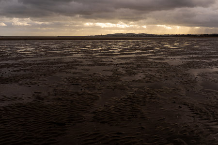 Dramatic, moody atmosphere over Sandymount Beach, Dublin, Ireland. Vast foreground of wet tidal...