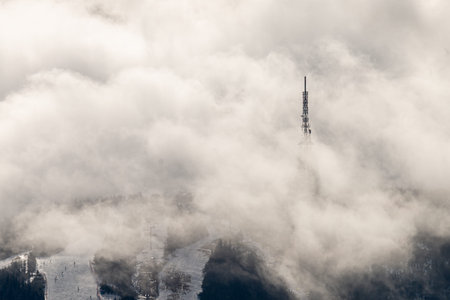 Photo of Radio and television broadcasting tower on Skrzyczne peak emerging from thick white clouds...