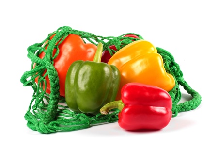 Fresh  sweet peppers in a green string bag isolated on white backgroundの写真素材