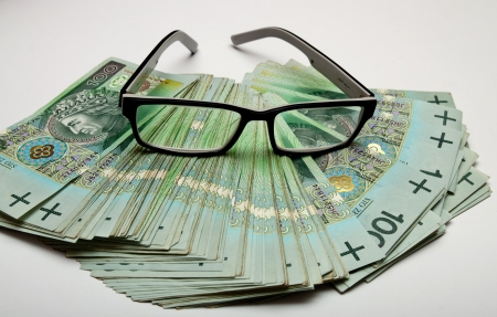 Glasses lying on the scattered moneyの写真素材