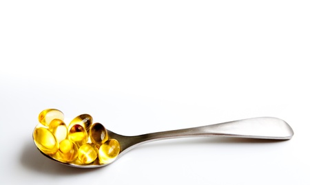 Golden pills on a spoon located horizontallyの写真素材