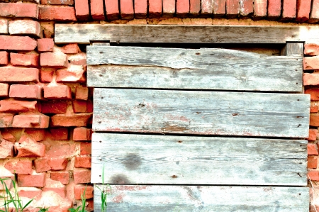 Grey shutter with wooden planks on a background of red wallの写真素材