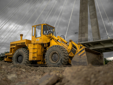 A yellow bulldozer next to a bridge.の写真素材