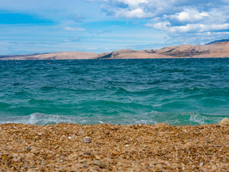 A blue beach in a mountainous bay. Blue Mediterranean Sea, rocky hills, beach. Pag, Croatia.の写真素材