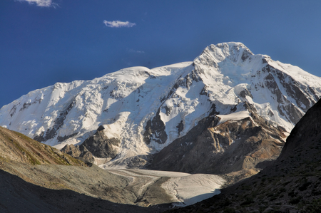 Panoramic view of sunlit snow-covered slopes of Tian-Shan Mountains, Kyrgyzstanの写真素材