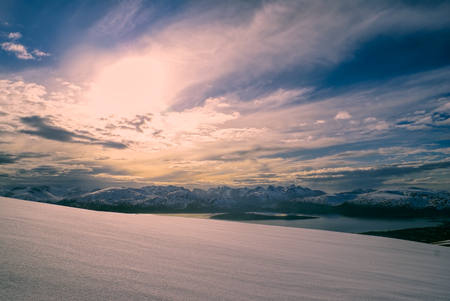 Picturesque view of snowy plain and mountains at sunset in Tromsdalstindenの写真素材