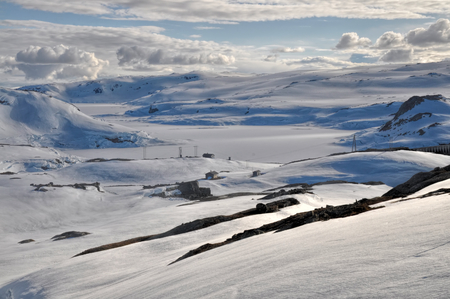 Houses scattered in the valley covered with snow in the mountains near Trolltunga, Norwayの写真素材