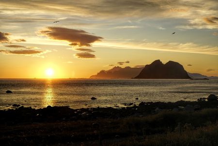 Breathtaking view of sunset over calm ocean and high mountainsの写真素材