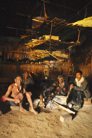 Nagaland, India - March 2012: Men sit around fire  in Nagaland, remote region of India. Documentary editorial.のeditorial素材