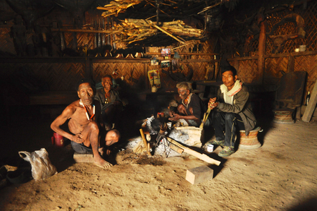 Nagaland, India - March 2012: Men sit around fire  in Nagaland, remote region of India. Documentary editorial.のeditorial素材