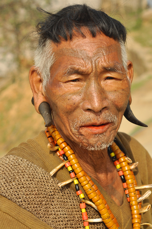 Nagaland, India - March 2012: Portrait of traditional Naga headhunter with painted face, pierced ears and necklace in Nagaland, remote region of India. Documentary editorial.のeditorial素材