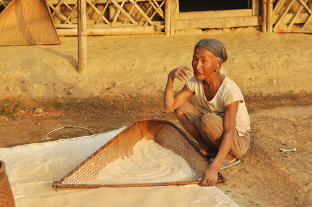 Nagaland, India - March 2012: Old woman sifts flour in Nagaland, remote region of India. Documentary editorial.のeditorial素材