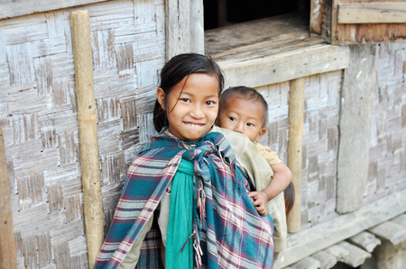 Nagaland, India - March 2012: Cute little girl carries her younger brother on her back in Nagaland, remote region of India. Documentary editorial.のeditorial素材