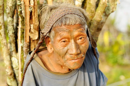 Nagaland, India - March 2012: Portrait of old man carrying heavy load in Nagaland, remote region of India. Documentary editorial.のeditorial素材