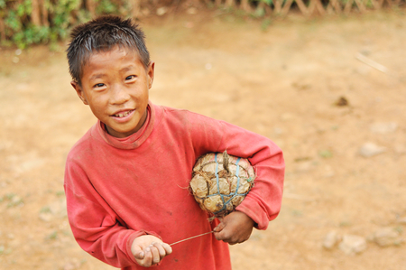Nagaland, India - March 2012: Small boy with self-made ball plays football in Nagaland, remote region of India. Documentary editorial.のeditorial素材