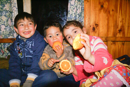Isla Laitec, Chile - September 2008: Small native children eat oranges in wooden house in Chile. Documentary editorial.のeditorial素材