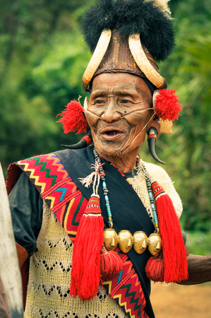 Mon, Nagaland - April 2012: Photo of old talking man in traditional costume with hat and large plugs in ears at Aoleang festival in Mon, Nagaland. At this festival people can see indigenous dances and games. Documentary editorial.のeditorial素材