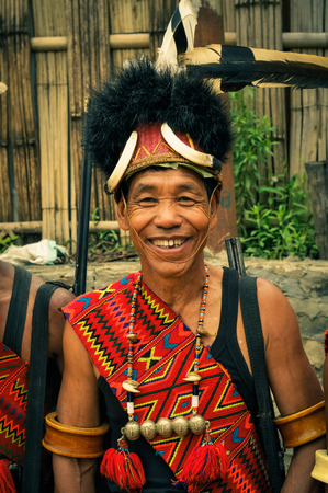 Mon, Nagaland - April 2012: Smiling man in costume and hat made of fur poses to photocamera at Aoleang festival in Mon, Nagaland. This festival showcases rich cultural heritage of this country. Documentary editorial.のeditorial素材