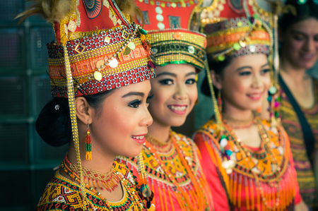 Makale, Indonesia - May 2015: Three beautiful girls dressed in traditional colourful costumes with jewellery and large hats smile during wedding in Makale, capital city of Tana Toraja Regency, South Sulawesi, Indonesia. Documentary editorial.のeditorial素材