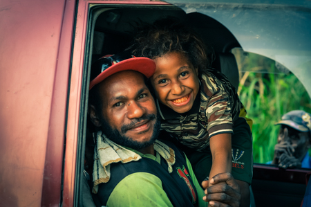Will-will, Papua New Guinea - July 2015: Smiling native man sits in car and poses with his young smiling son in Will-will, Nuku, Papua New Guinea. Documentary editorial.のeditorial素材