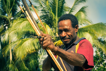 Will-will, Papua New Guinea - July 2015: Native man holds wooden bow and arrow and looks to photocamera in Will-will, Nuku, Papua New Guinea. Documentary editorial.のeditorial素材
