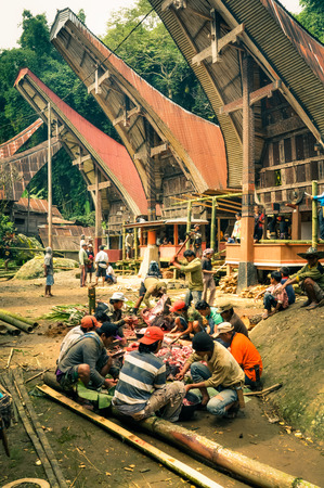 Toraja, Indonesia - June 2015: People sit on trunks of bamboo tree and cut meat in Toraja, Sulawesi region, Indonesia. Documentary editorial.のeditorial素材