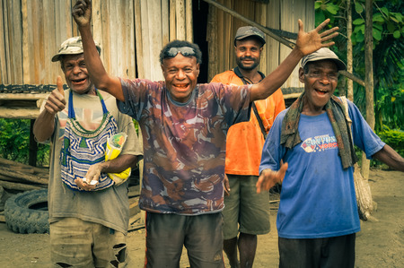 Will-will, Papua New Guinea - July 2015: Four native men smile and wave to photocamera in front of wooden house in Will-will, Nuku, Papua New Guinea. Documentary editorial.のeditorial素材