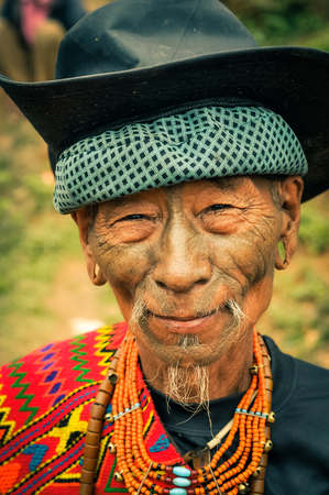 Mon, Nagaland - April 2012: Old native man with colourful necklace made of beads and black hat  smiles to photocamera at Aoleang festival in Mon, Nagaland. Documentary editorial.のeditorial素材
