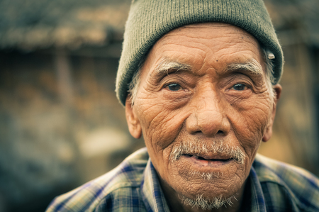 Wanching, Nagaland - April 2012: Old man with tanned and wrinkled face wears cap on his head and looks to photocamera at traditional Aoleang festival in Wanching, Nagaland. Documentary editorial.のeditorial素材