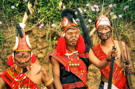 Mon, Nagaland - April 2012: Native men with black colour on their faces hold rifles and pose in traditional costumes and hats with fur at Aoleang festival in Mon, Nagaland. Documentary editorial.のeditorial素材
