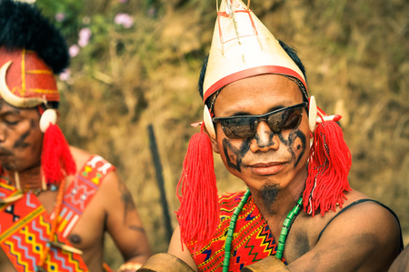 Mon, Nagaland - April 2012: Photo of young man dressed in traditional colourful costume and hat wearing sunglasses at Aoleang festival in Mon, Nagaland. Documentary editorial.のeditorial素材