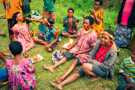 Kubor Range, Papua New Guinea - July 2015: Native people sit on ground and put colours on their faces during traditional dances in Kubor Range, Papua New Guinea. Documentary editorial.のeditorial素材