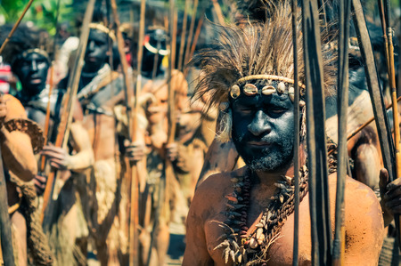 Wabag, Papua New Guinea - August 2015: Native half-naked man with closed eyes with black colour on face holds wooden arrow and bow and wears headband with feathers during traditional Enga cultural show in Wabag, capital of Enga Province, Papua New Guinea.のeditorial素材